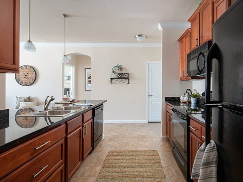A modern kitchen with wooden cabinets and black appliances in an open layout.