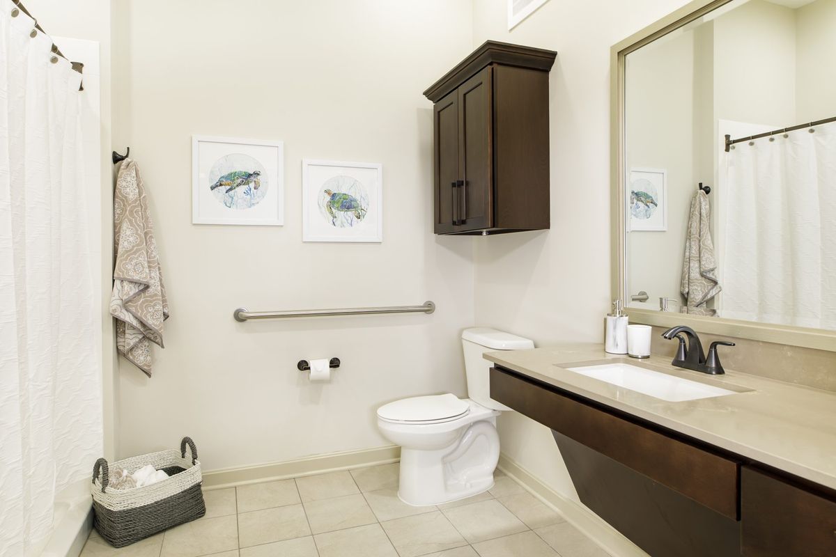 A modern bathroom with a toilet, sink, and mirror.