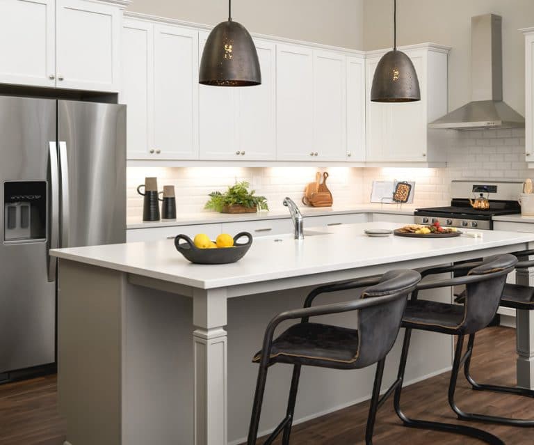 A modern kitchen with a central island, bar stools, and sleek pendant lighting.