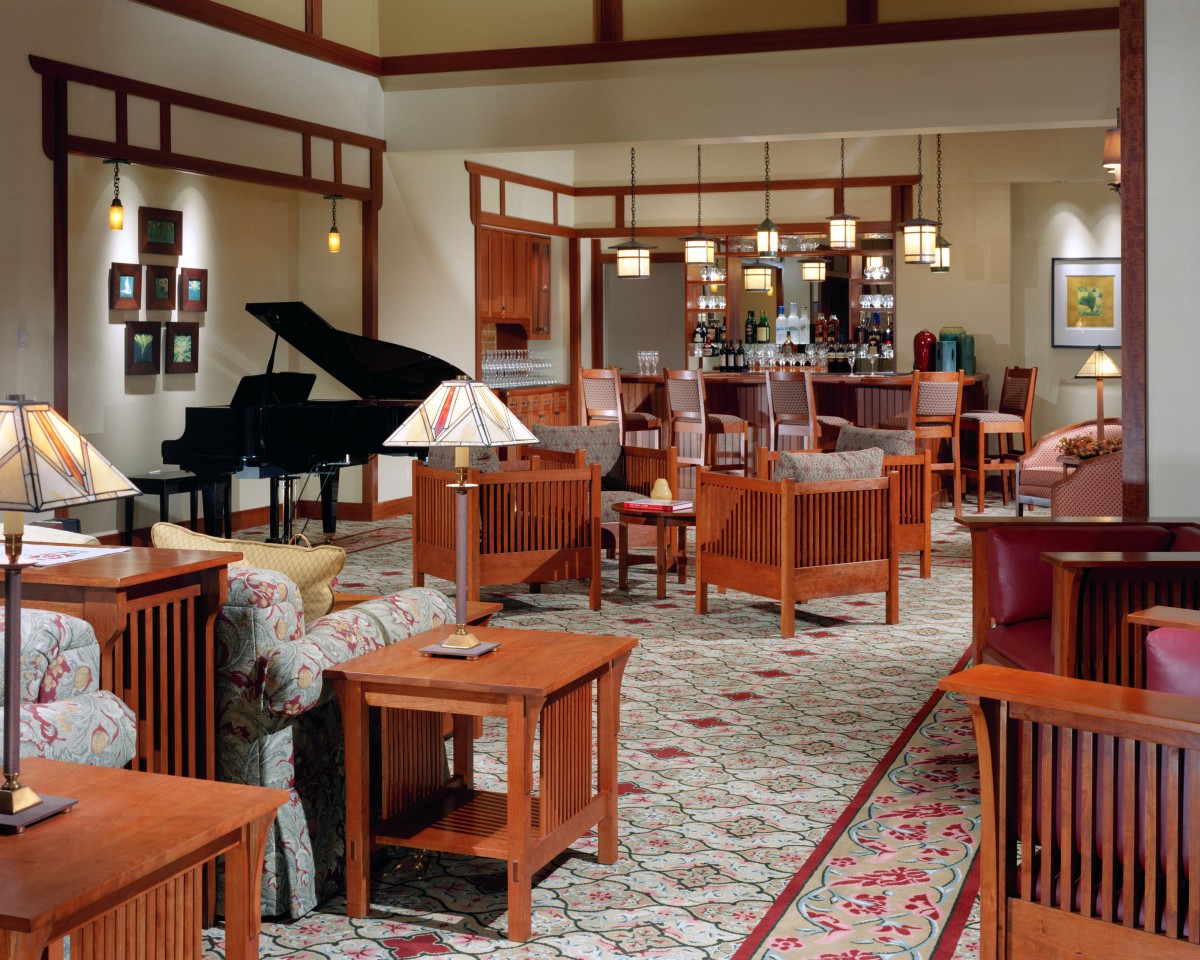 A spacious living room with a modern decor featuring wooden furniture and a grand piano.