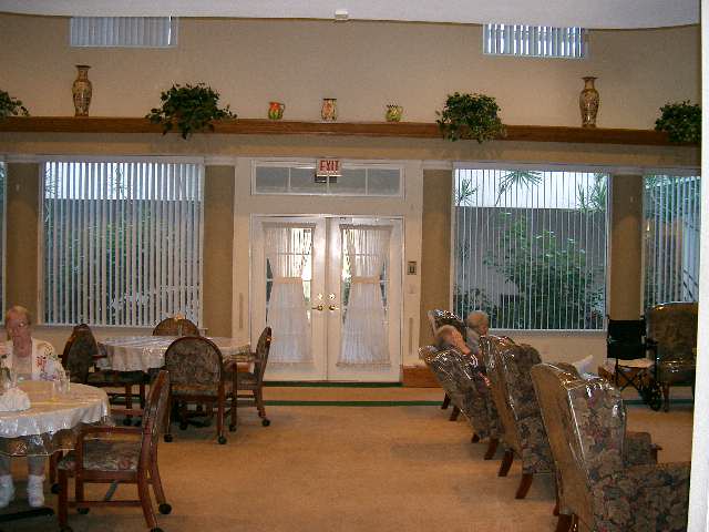 An elegant dining area with neatly arranged tables and chairs leading to glass doors, adorned with plants.