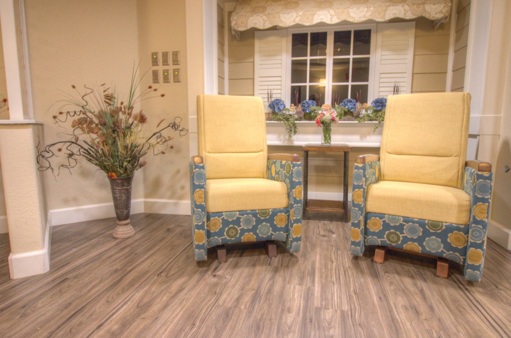 A cozy living room setting featuring two yellow upholstered chairs and a flower arrangement on a wooden floor.