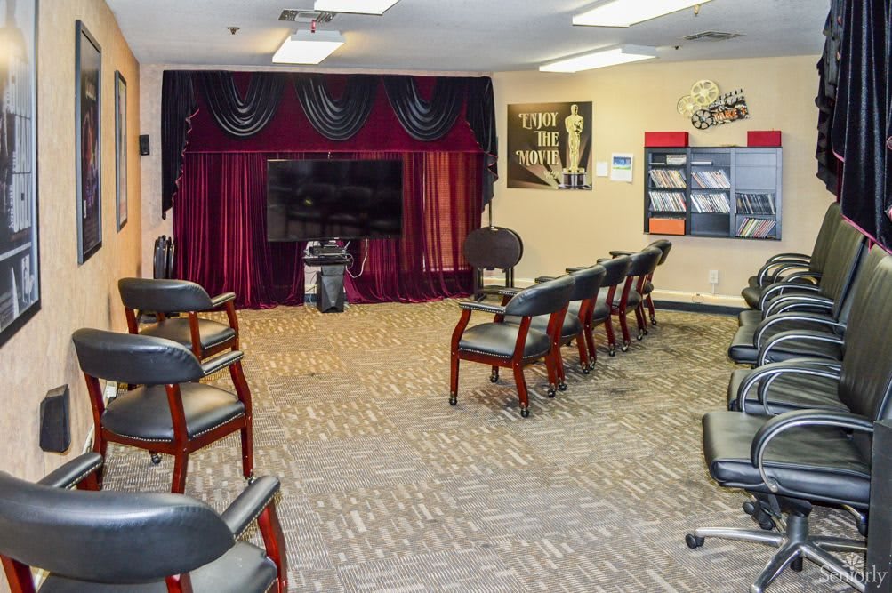 A waiting area with chairs arranged around a television, decorated with curtains and magazines on display.
