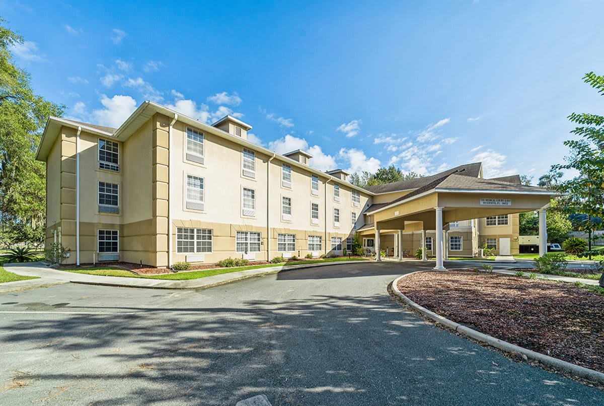 A three-story hotel building with a driveway under a clear blue sky.