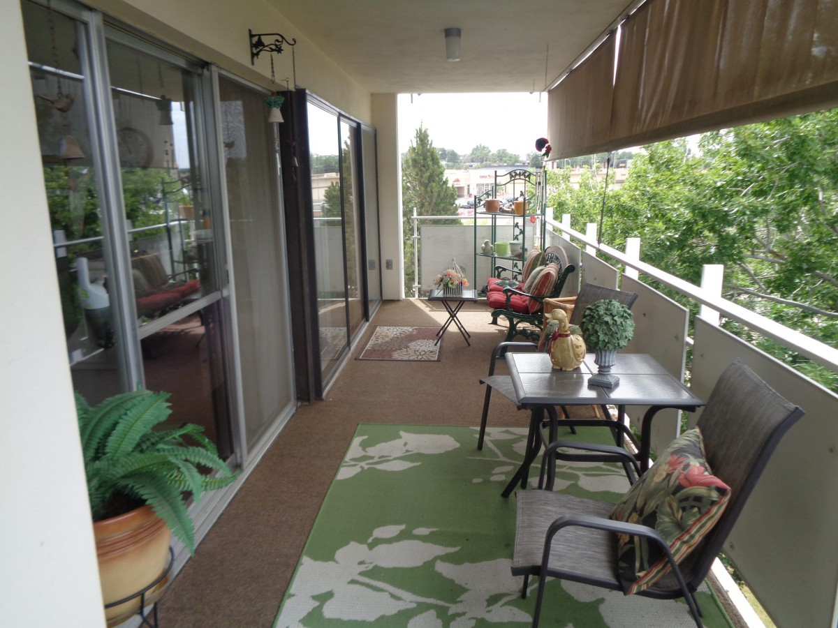 A cozy balcony with outdoor seating and greenery.