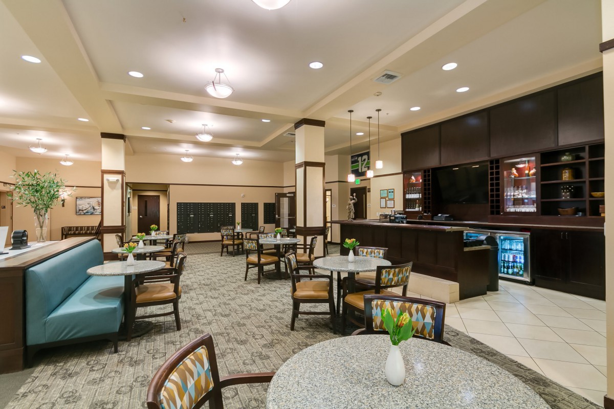 A spacious dining area with tables and chairs, featuring a bar counter and elegant lighting.