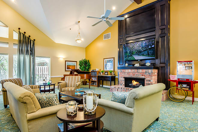 A cozy living room featuring a fireplace, comfortable seating, and a grand piano.