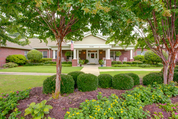 A well-landscaped building entrance surrounded by trees and bushes.