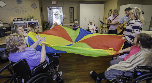 Seniors enjoying a lively music session while engaging in a fun parachute activity.