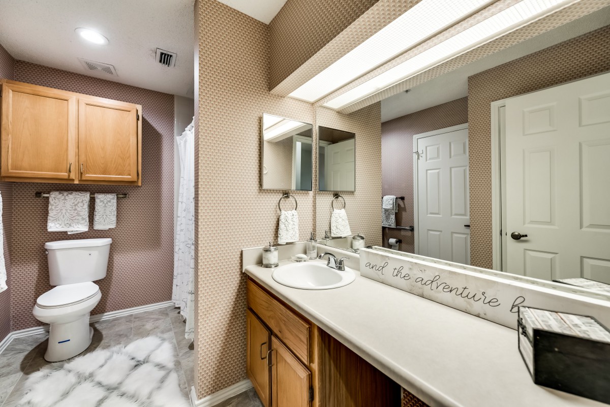 A well-lit bathroom featuring a large mirror, a sink with a spacious countertop, and neatly arranged towels.