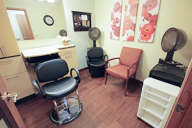 A cozy hair salon interior with chairs and a wall-mounted mirror.