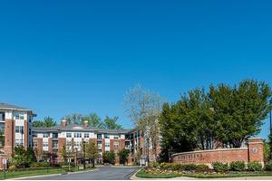 A residential apartment complex surrounded by trees under a clear blue sky.