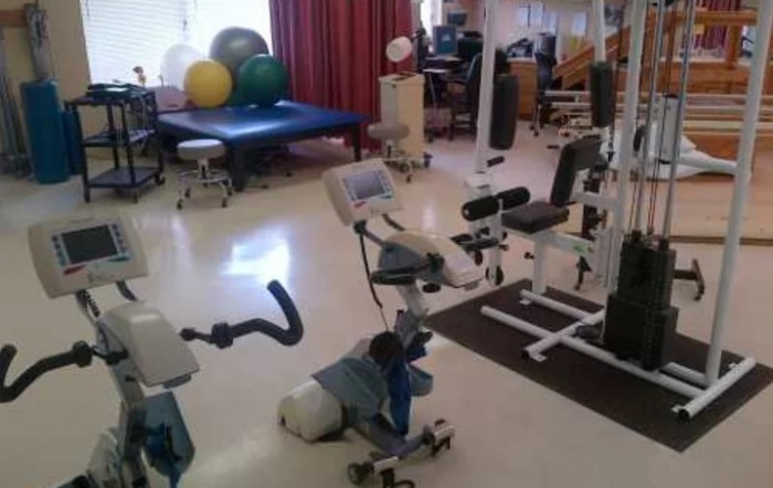 A physical therapy room equipped with exercise machines and therapy balls.