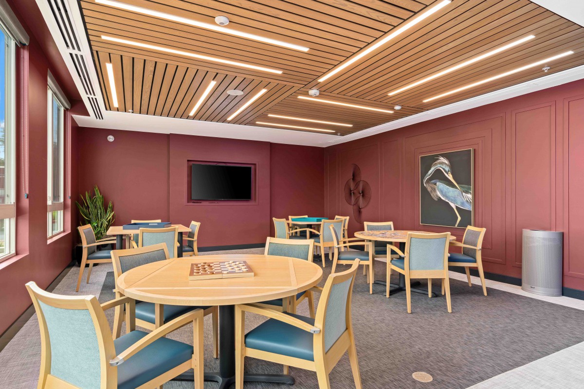 A modern lounge area with tables, chairs, a TV, and decorative artwork on the walls.