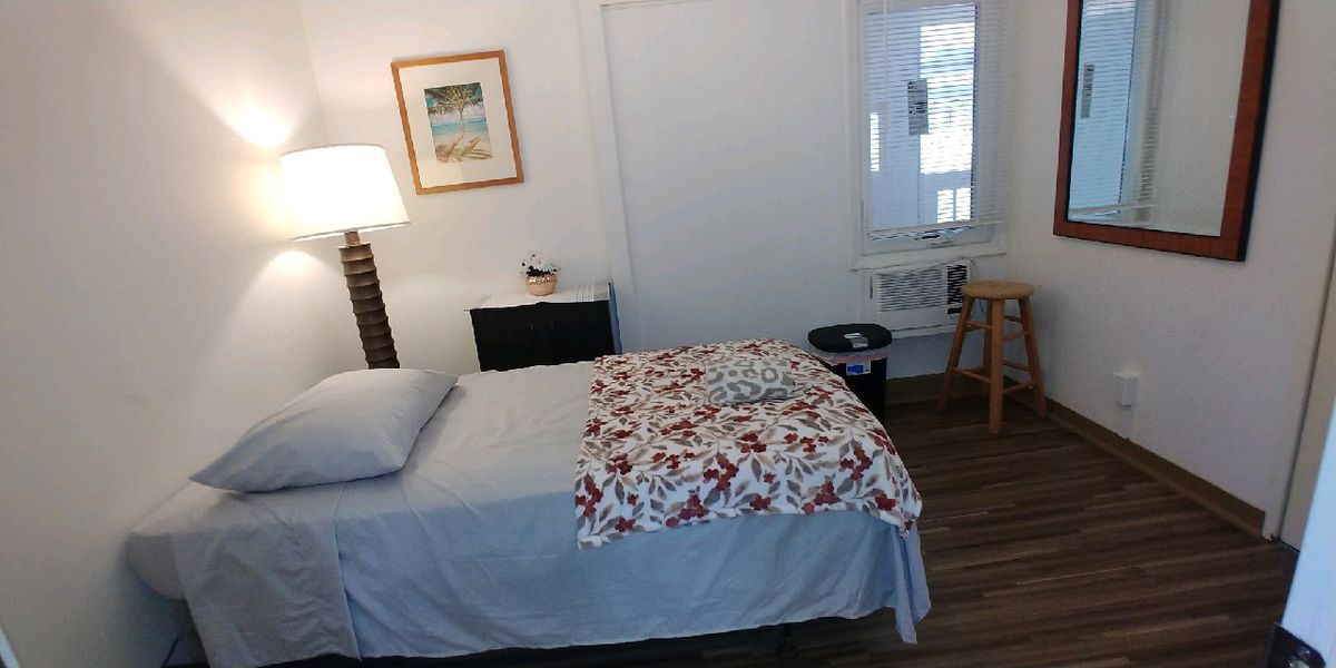 A cozy bedroom with a neatly made bed, bedside lamp, and simple decor.