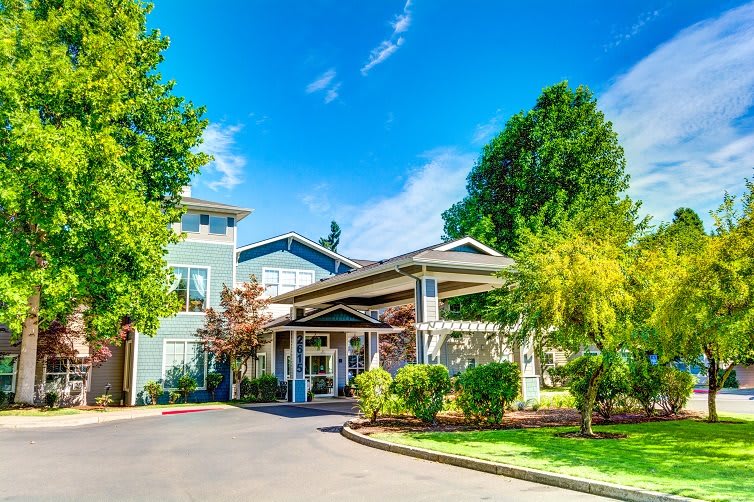 A picturesque building entrance surrounded by lush greenery and a clear blue sky.