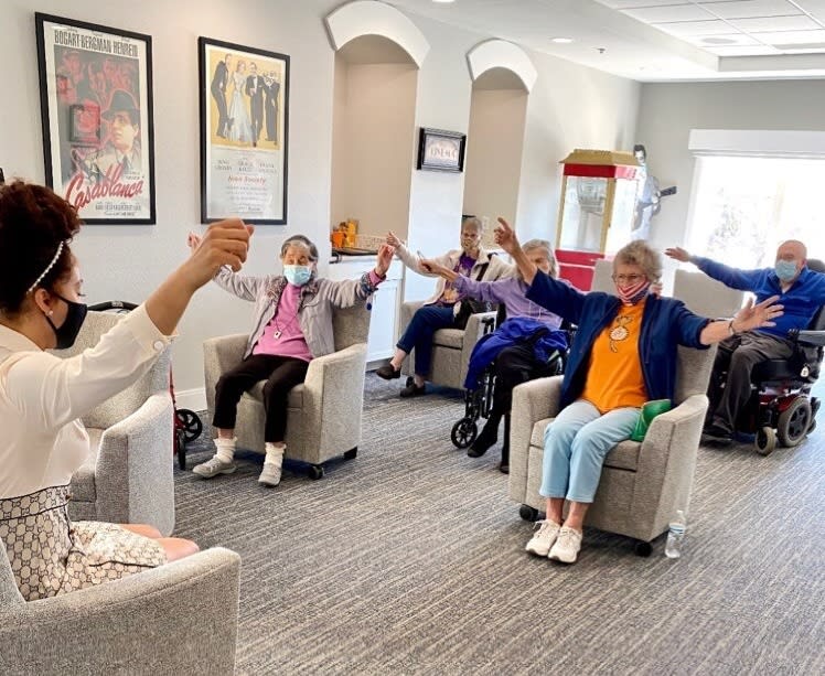 A group of seniors participating in a seated exercise class indoors.