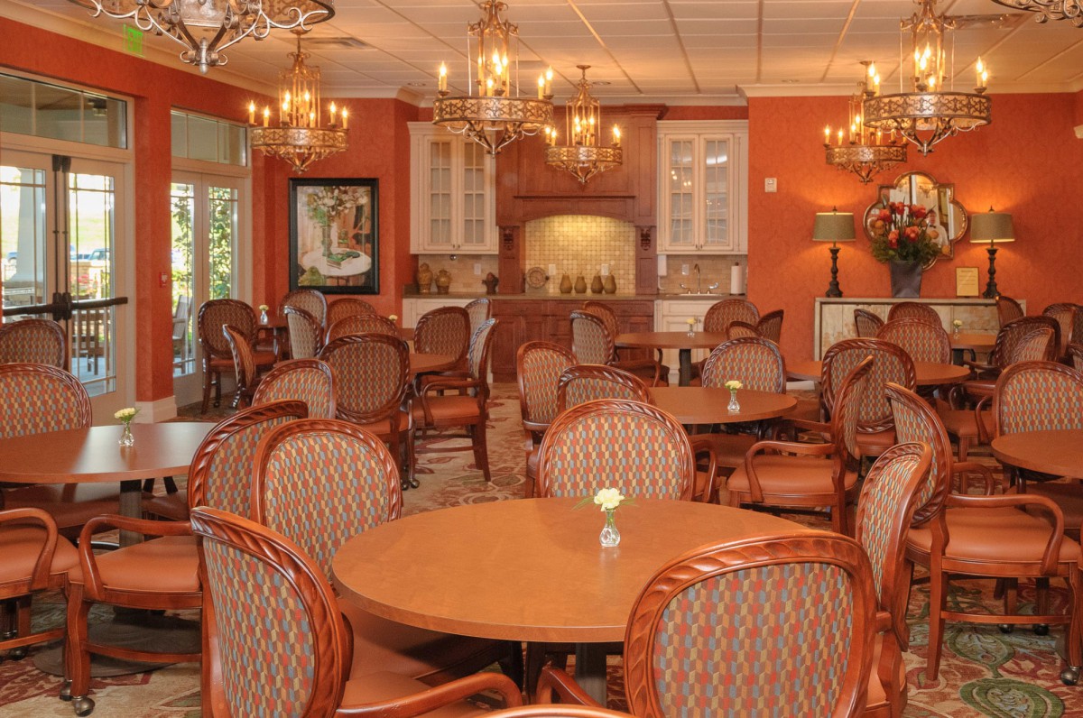 A stylishly decorated restaurant dining area with round wooden tables and upholstered chairs.