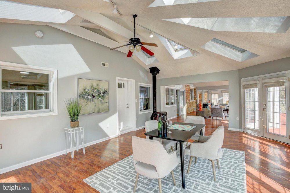 A modern dining room with skylights and a ceiling fan, featuring contemporary decor and hardwood floors.