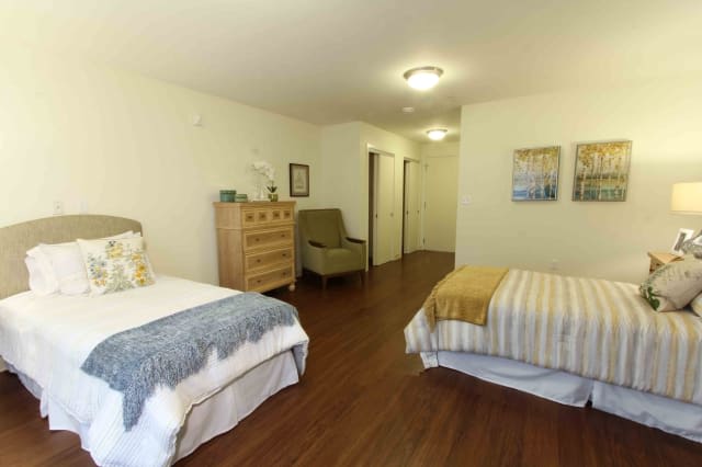 A cozy bedroom featuring twin beds with modern decor and wooden flooring.