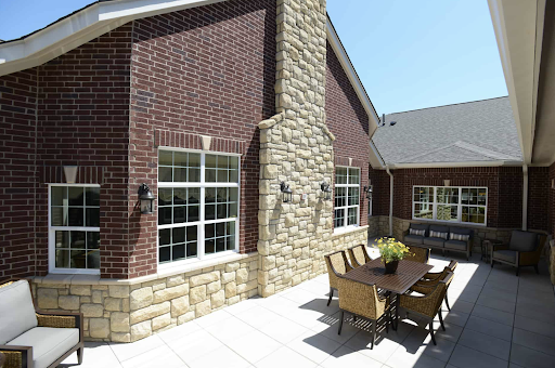 A beautifully designed exterior of a residential building featuring a mix of brick and stone materials, with an inviting outdoor seating area.