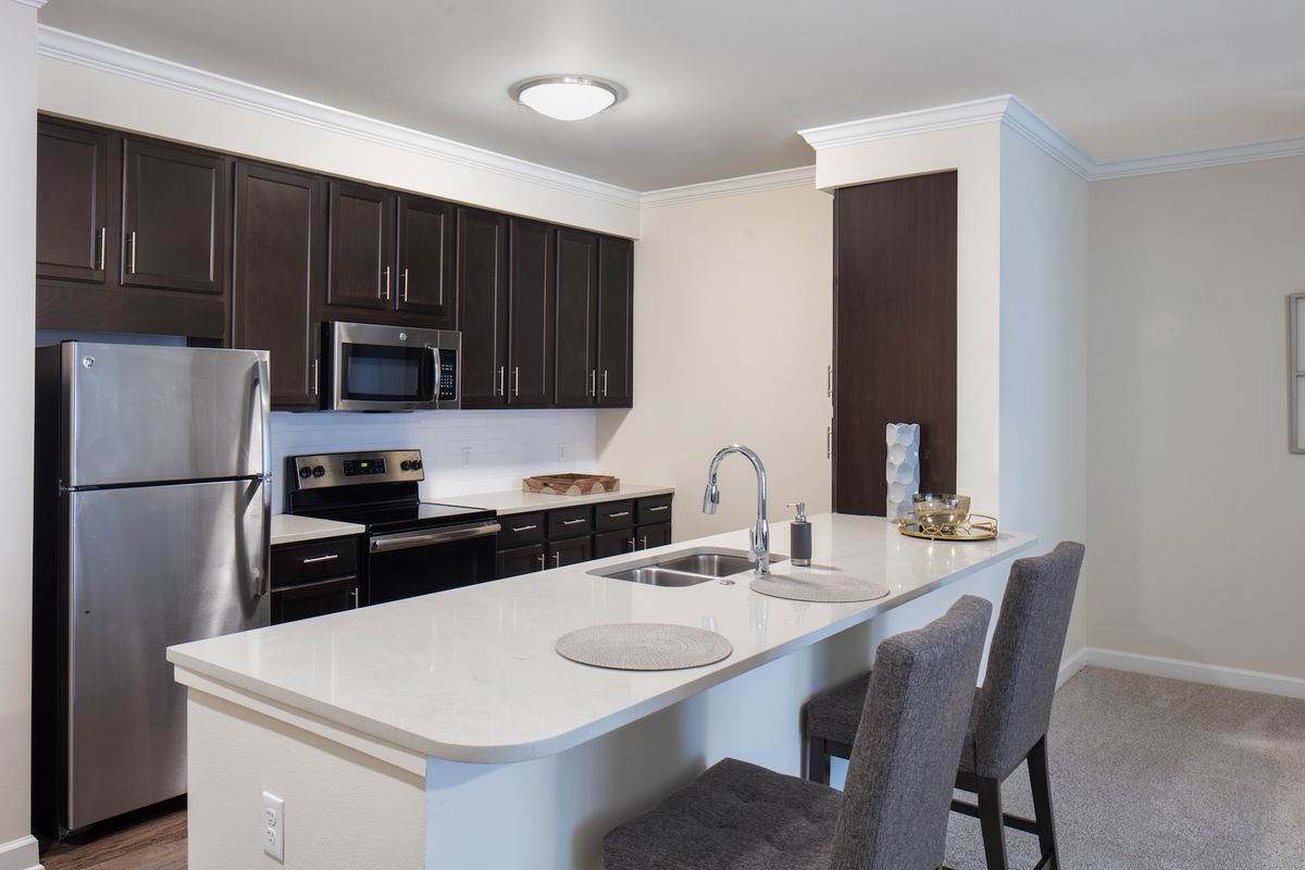 A modern kitchen featuring stainless steel appliances and an open countertop with bar stools.