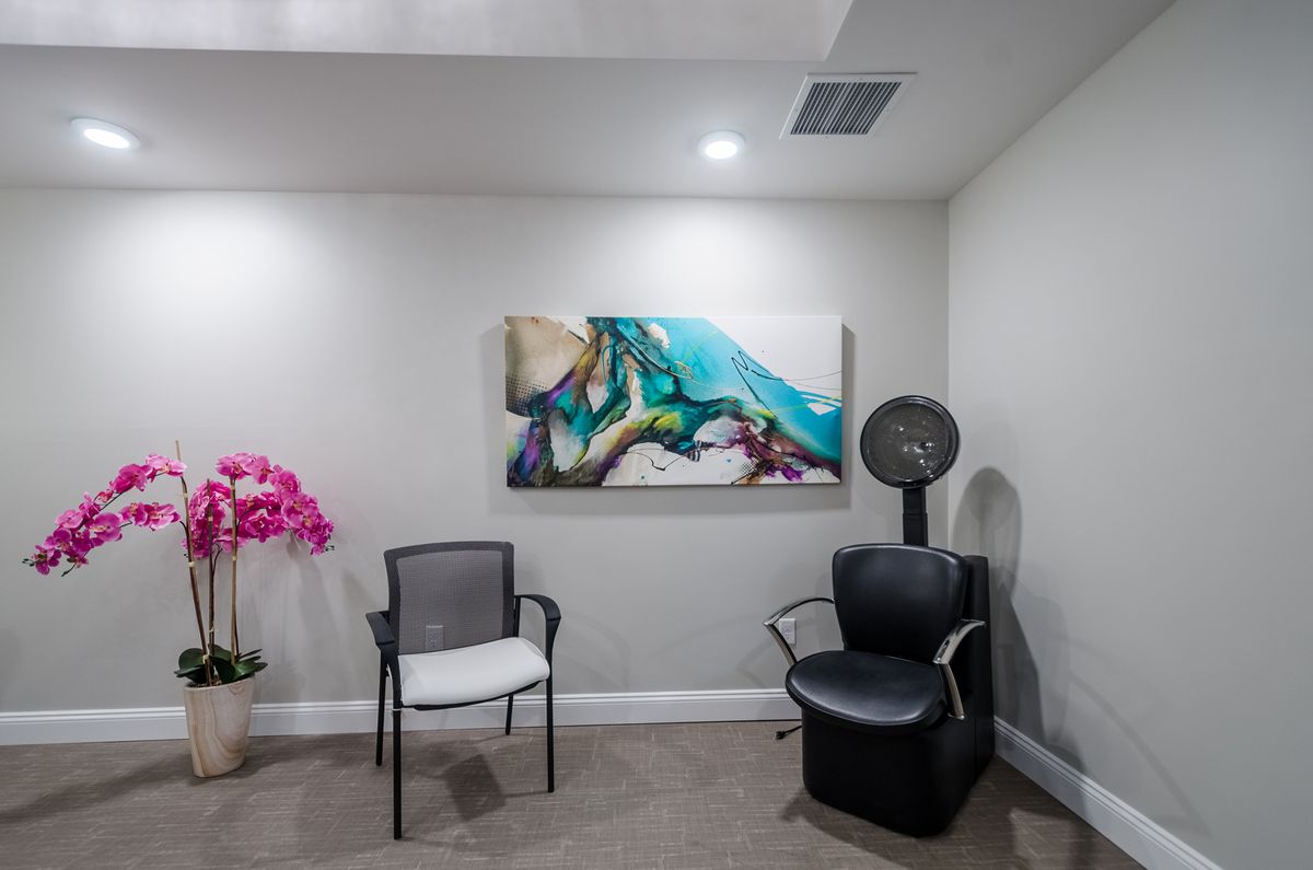 A modern waiting room featuring chairs, vibrant artwork, and an orchid.