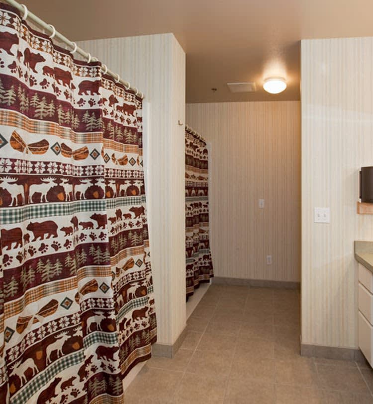 A clean public bathroom with patterned shower curtains and a sink area.