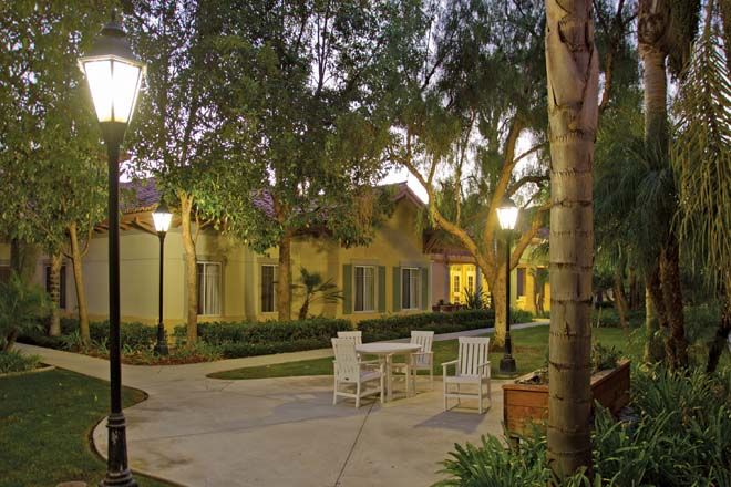 A tranquil outdoor garden setting with chairs and tables under evening lights.