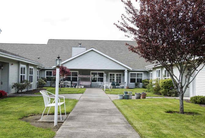 A residential building with a well-maintained lawn and pathway leading to the entrance.