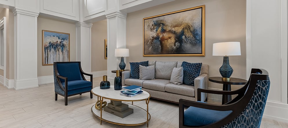 A stylish living room features a comfortable sofa, elegant armchairs, a decorative coffee table, and a striking large artwork on the wall.