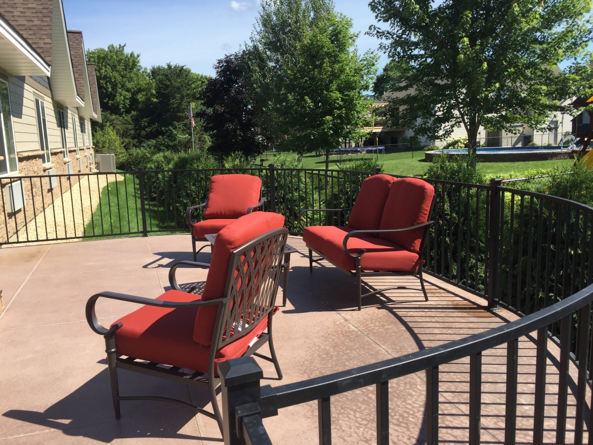 A sunny patio with red cushioned outdoor furniture.