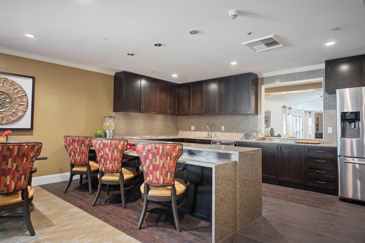 A modern kitchen interior featuring dark cabinetry and a sleek countertop with stylish bar stools.