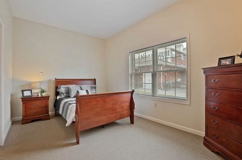 A cozy bedroom with a large window and wooden furniture.