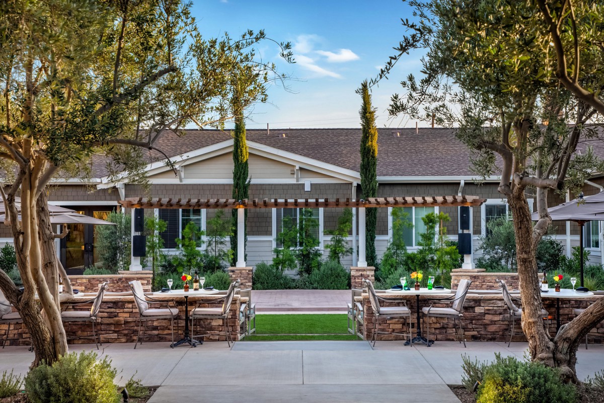 A beautiful garden setting with outdoor seating and a pergola, surrounded by lush greenery.