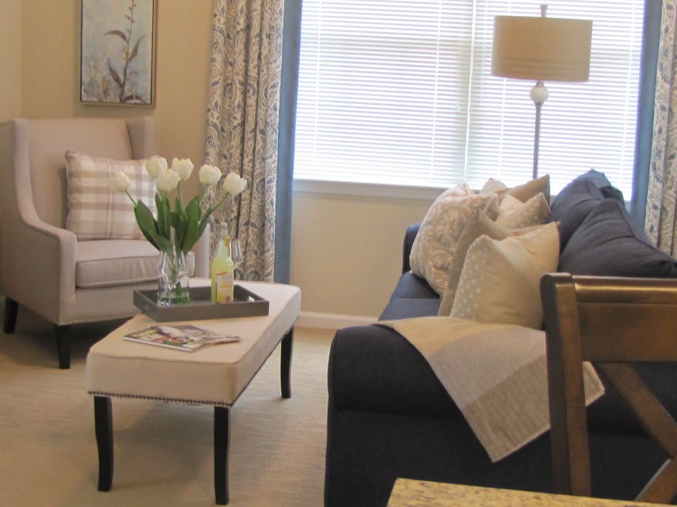 A cozy living room with a blue sofa, beige coffee table, and white tulips in a vase.
