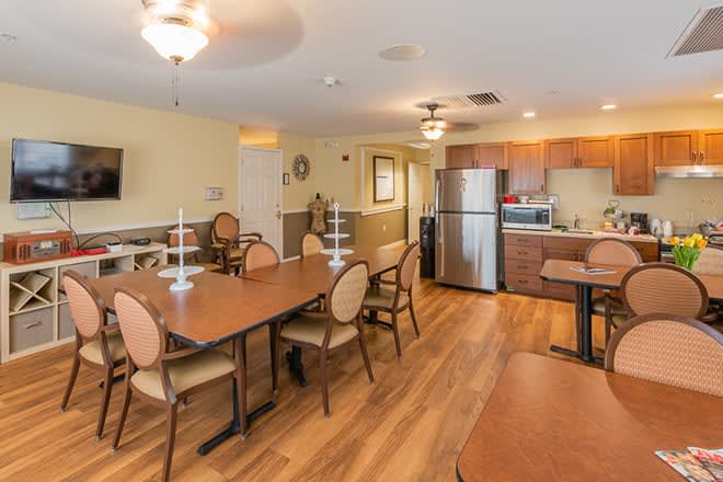 A cozy dining area with a kitchen, featuring wooden tables and chairs and modern appliances.
