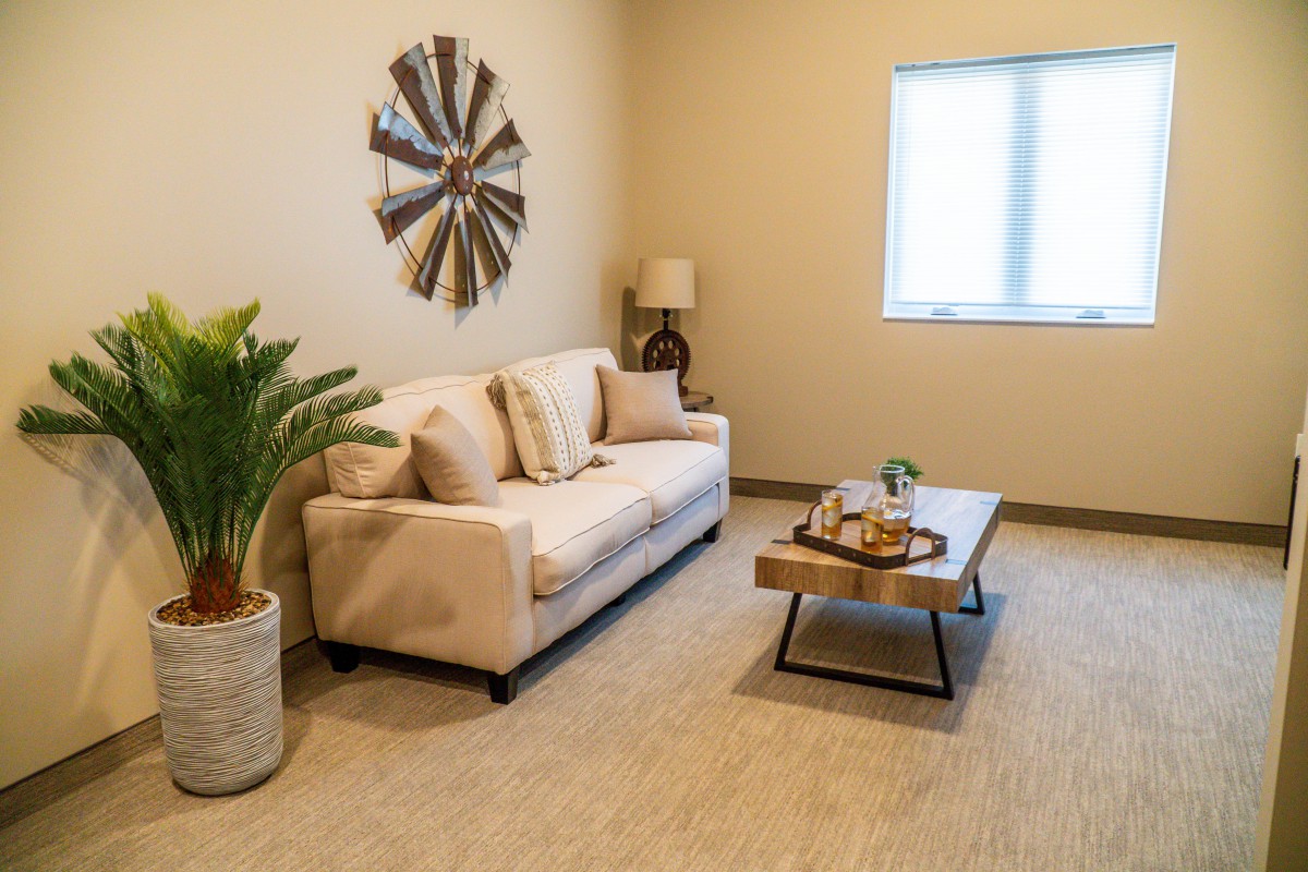 A cozy living room with a beige sofa, coffee table, and decorative elements including wall art and an indoor plant.