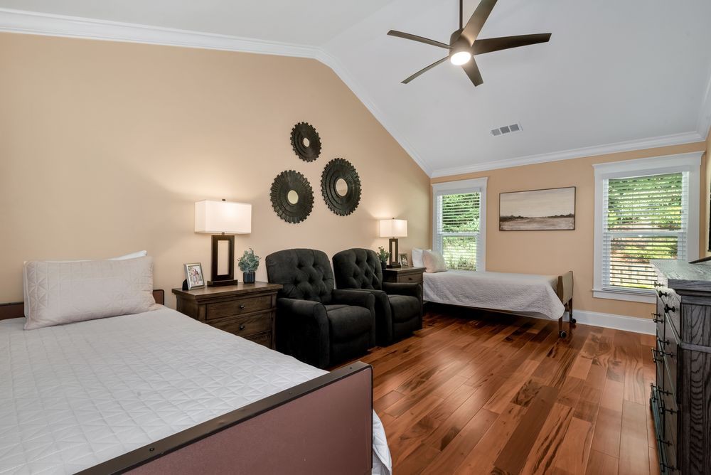 A modern bedroom with twin beds, armchairs, and elegant wall art.