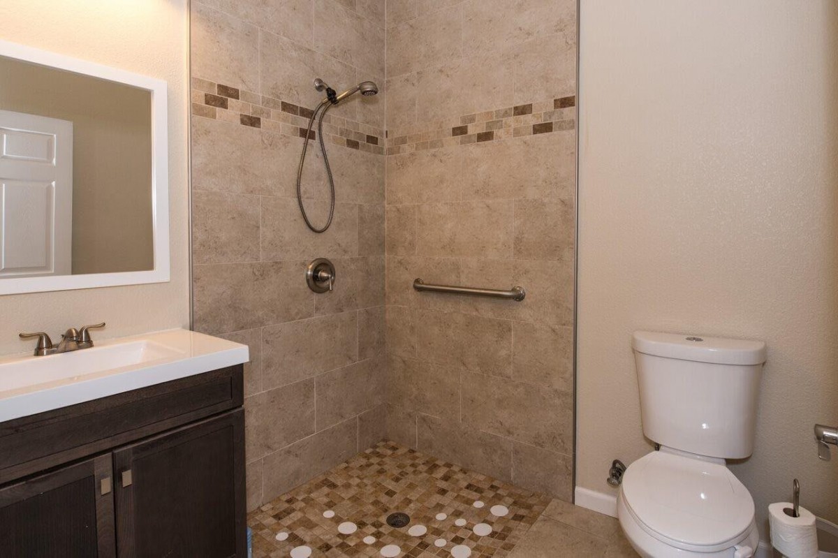 A modern bathroom with a walk-in shower and tiled flooring.