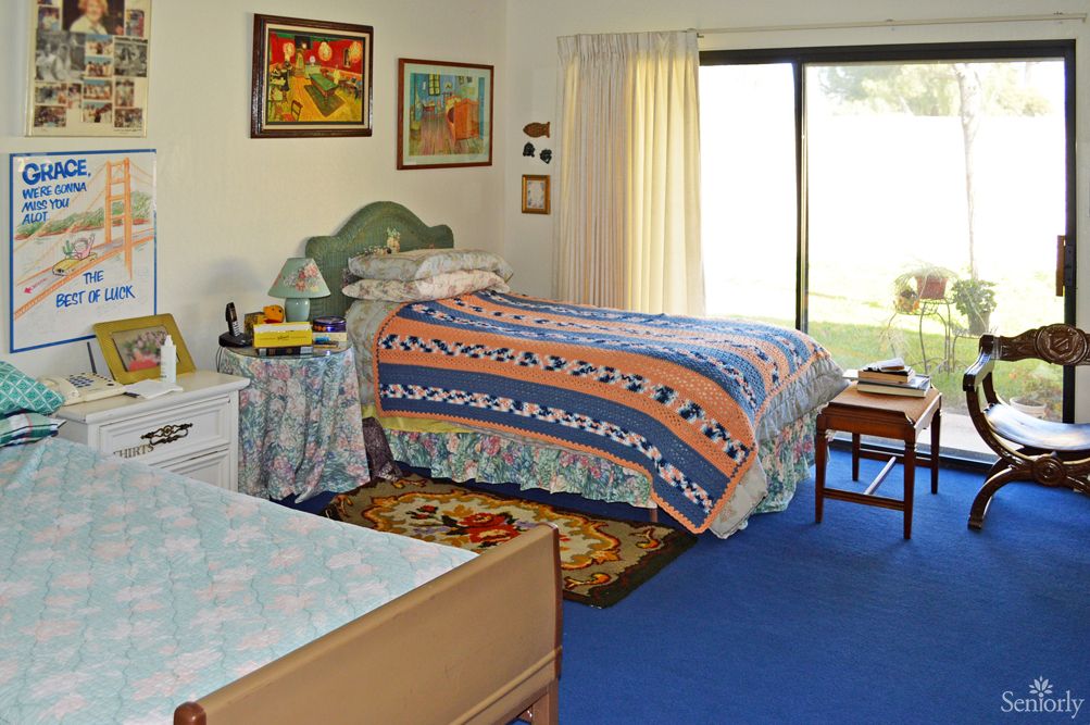 A cozy bedroom with twin beds adorned with colorful quilts and decorated with various artworks on the walls.