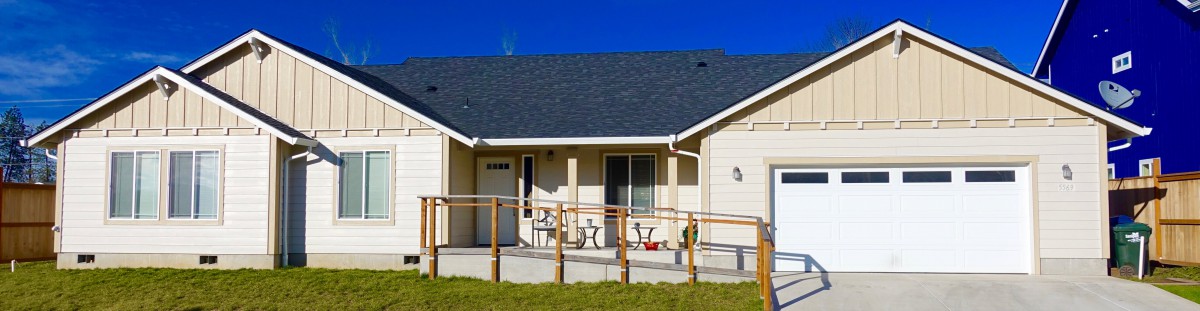 A single-story house with a ramp leading to the entrance, set against a clear blue sky.