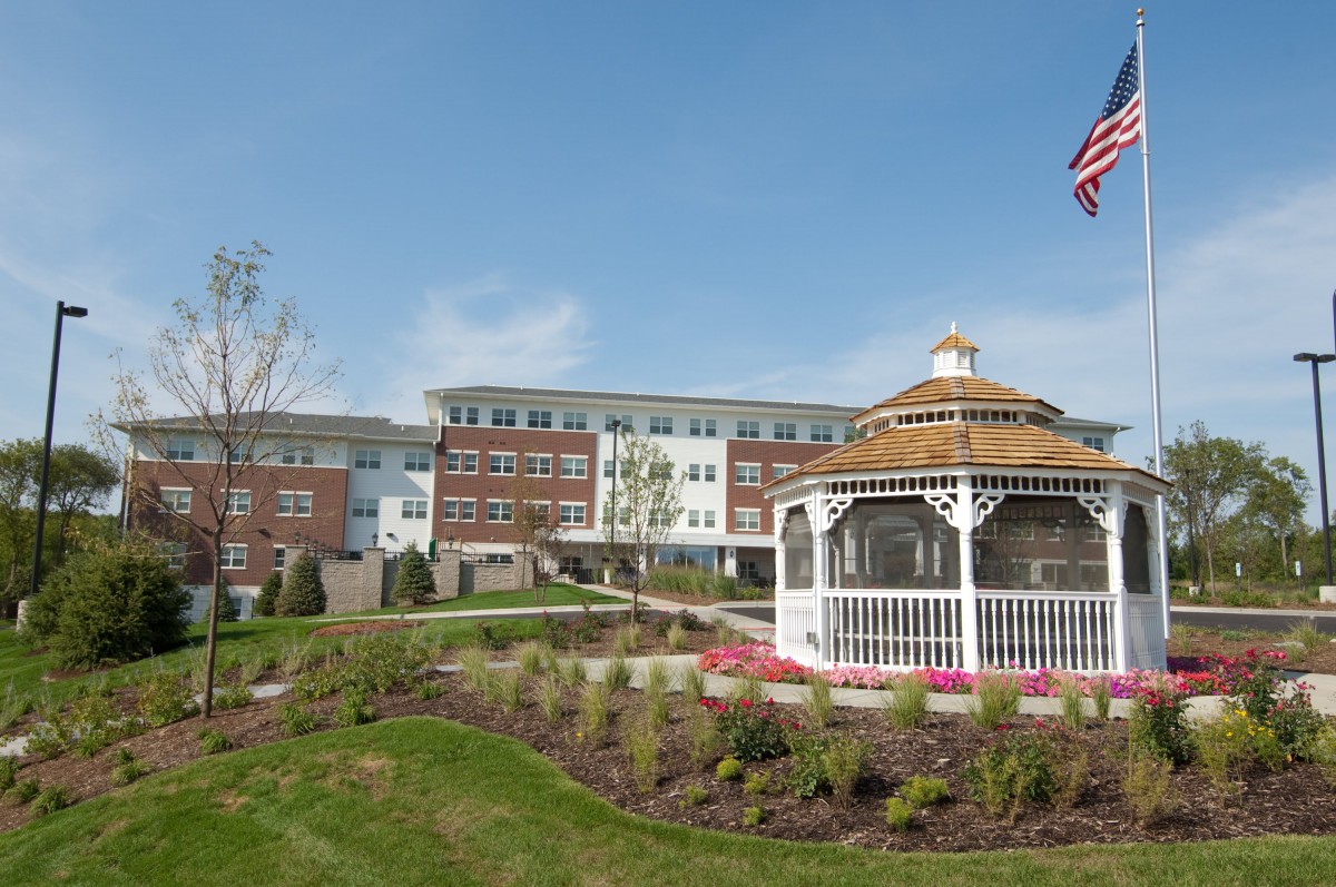 A scenic view of a building with a gazebo and well-maintained landscaping under a clear blue sky.