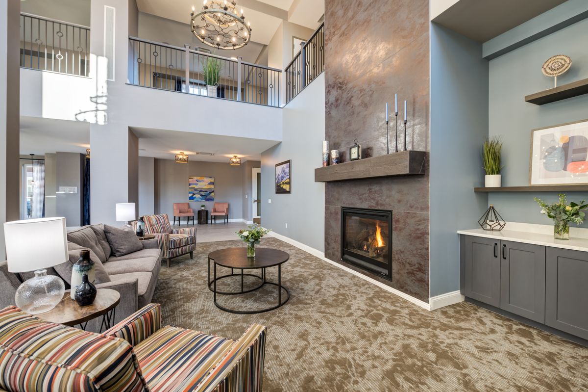A modern living room with a high ceiling, featuring a cozy fireplace, stylish chandelier, and comfortable seating area.
