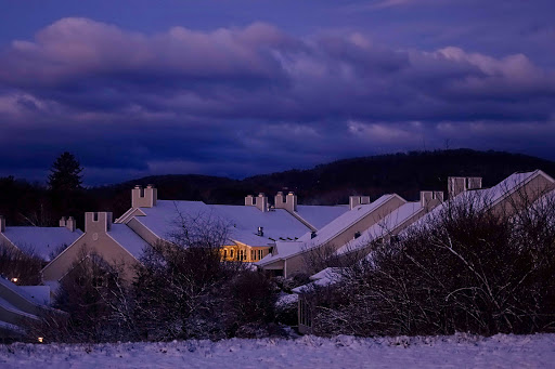 A serene winter evening view of houses blanketed in snow under a twilight sky.