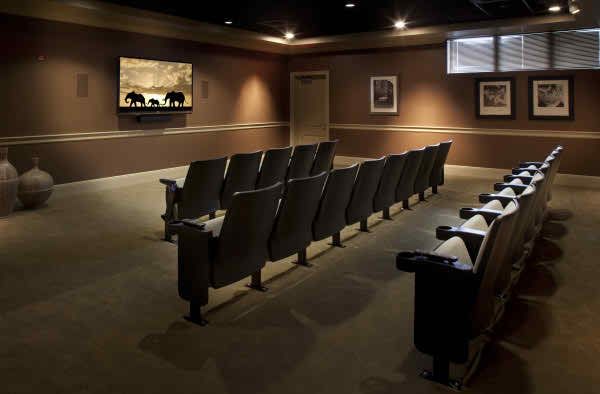 A cozy home theater with rows of comfortable seating facing a projector screen.