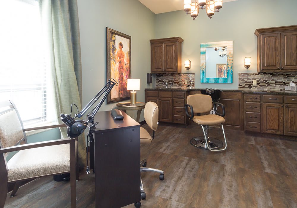 A stylish salon interior featuring a work desk, chair, and cabinetry with decorative artwork.