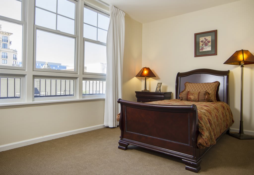 A cozy bedroom with a wooden bed and nightstand, featuring a lamp and decor.