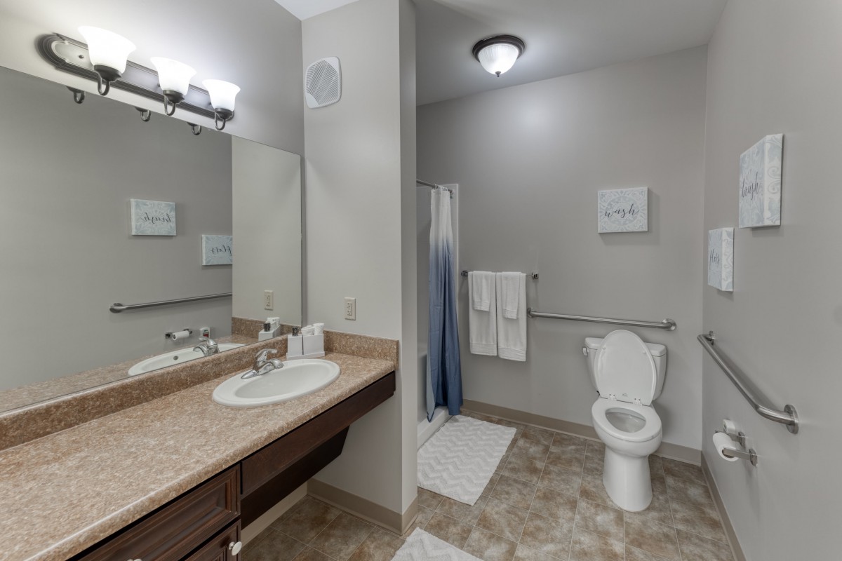 Modern bathroom with a sink, mirror, toilet, and shower area.