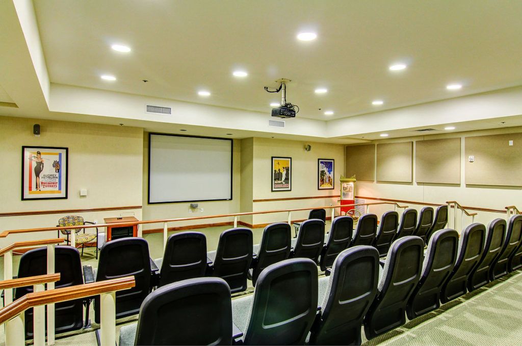 A well-equipped conference room with rows of seating, a projector setup, and a screen for presentations.